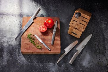 Global Classic 7-Piece Takashi Knife Wood Block Set displayed on countertop with nearby tomatoes and cutting board