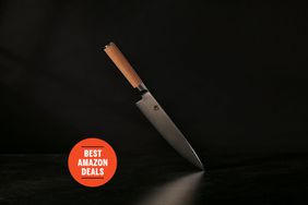 Shun Classic Chefâs 8-Inch Knife appearing to hover in air as tip of blade touches a black surface