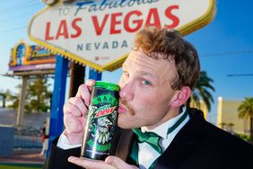 Thomas Rank kisses a can of Hard Mtn Dew in front of the Welcome to Las Vegas sign
