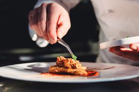 A chef garnishes a plate at restaurant